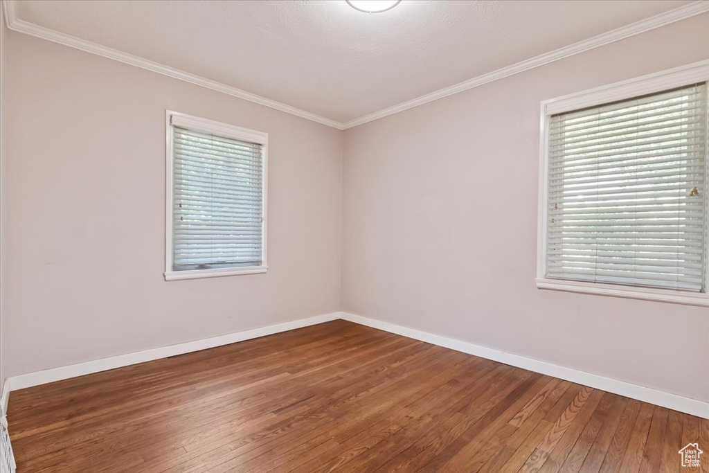 Unfurnished room with wood finished floors and crown molding