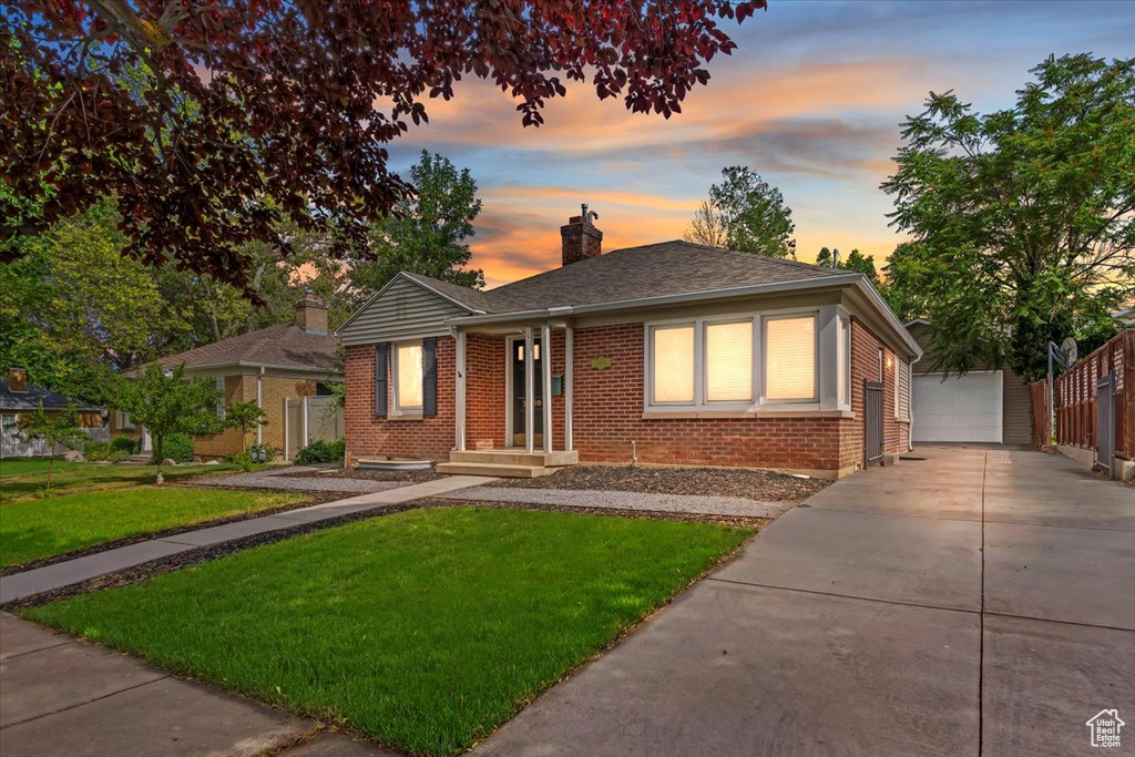 View of front of home with brick siding, an outdoor structure, a chimney, a garage, and a shingled roof