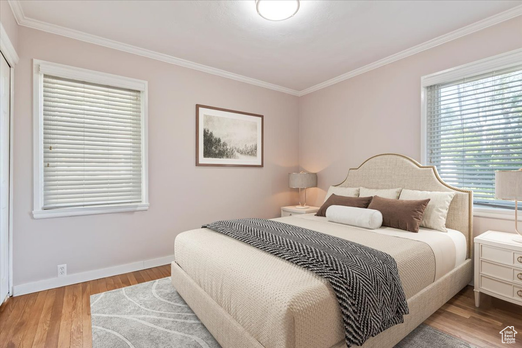 Bedroom with multiple windows, wood finished floors, and ornamental molding