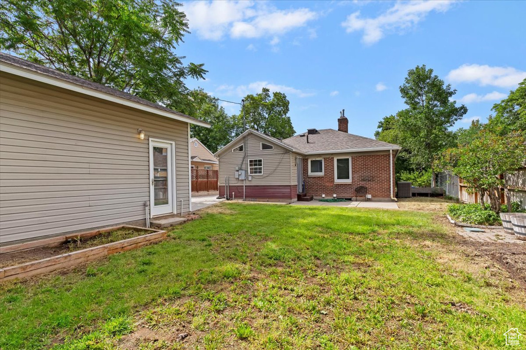 Back of house with a patio area, a chimney, brick siding, and a garden