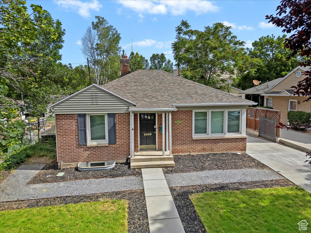 Bungalow-style house with brick siding, roof with shingles, and a chimney