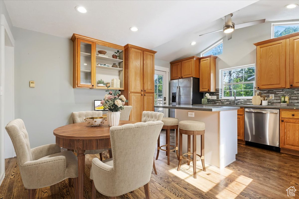 Kitchen featuring appliances with stainless steel finishes, healthy amount of natural light, a kitchen bar, lofted ceiling, and a ceiling fan