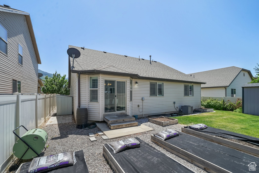 Back of house featuring a fenced backyard and a shingled roof