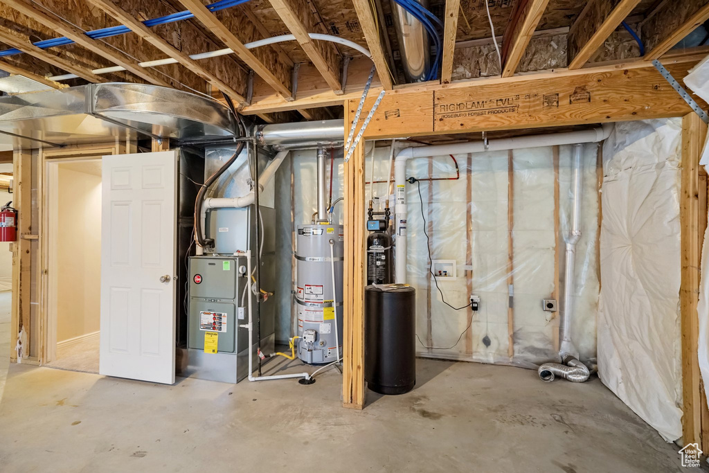 Unfinished basement with strapped water heater, a water softener, and heating unit