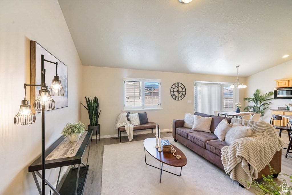 Living area with light wood-type flooring, lofted ceiling, and a chandelier