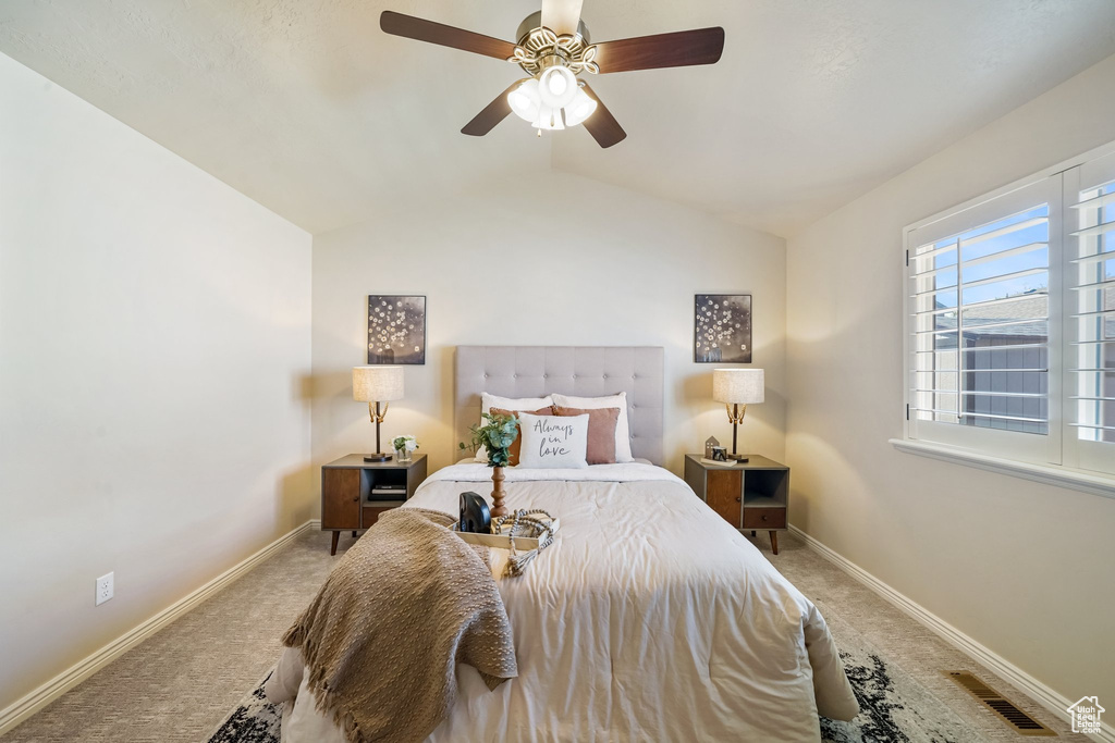 Carpeted bedroom with vaulted ceiling and a ceiling fan