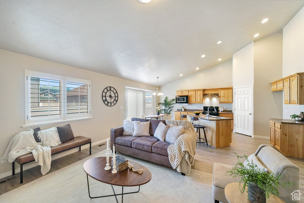 Living room with light wood-type flooring, recessed lighting, and high vaulted ceiling
