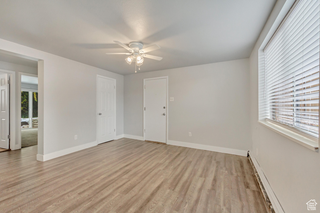 Unfurnished room featuring light wood-type flooring, a ceiling fan, and baseboards