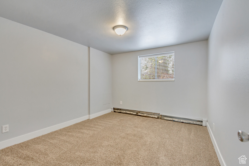 Unfurnished room with carpet floors, baseboard heating, a textured ceiling, and baseboards