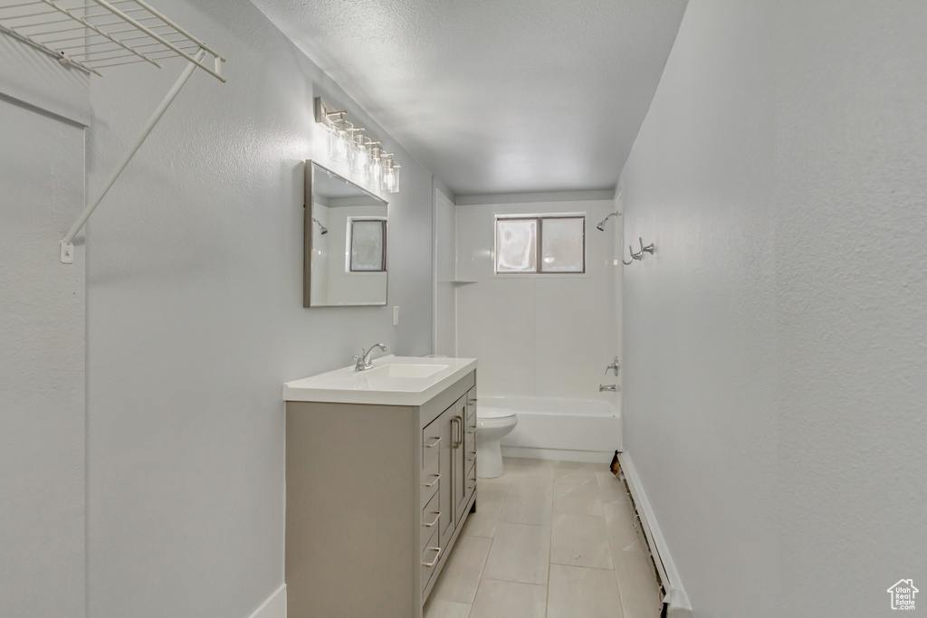 Bathroom with vanity, toilet, tile patterned flooring, baseboards, and tub / shower combination
