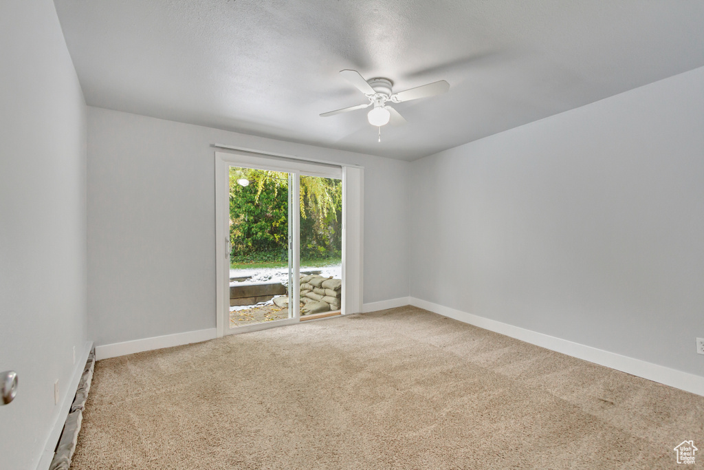 Empty room with a ceiling fan, carpet flooring, baseboard heating, and baseboards