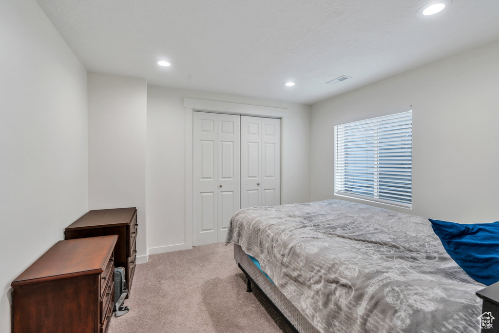 Bedroom featuring recessed lighting, light colored carpet, and a closet