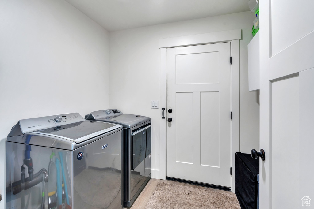 Laundry area with washing machine and dryer and light wood-style floors