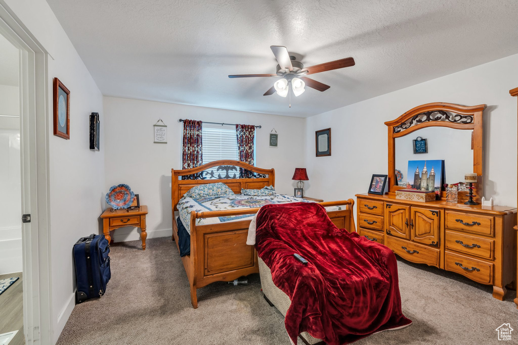 Bedroom with light carpet, ceiling fan, and a textured ceiling