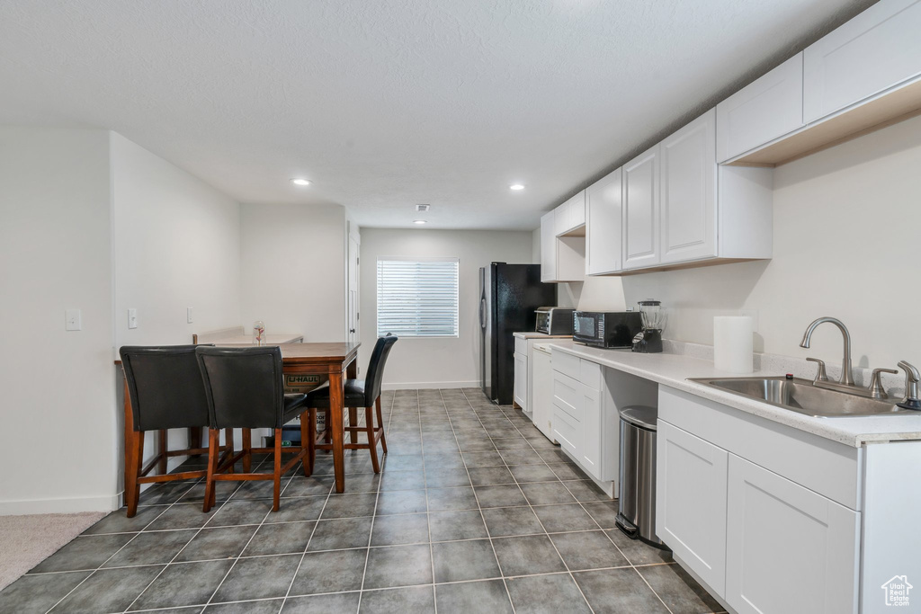 Kitchen featuring freestanding refrigerator, white cabinetry, recessed lighting, and light countertops