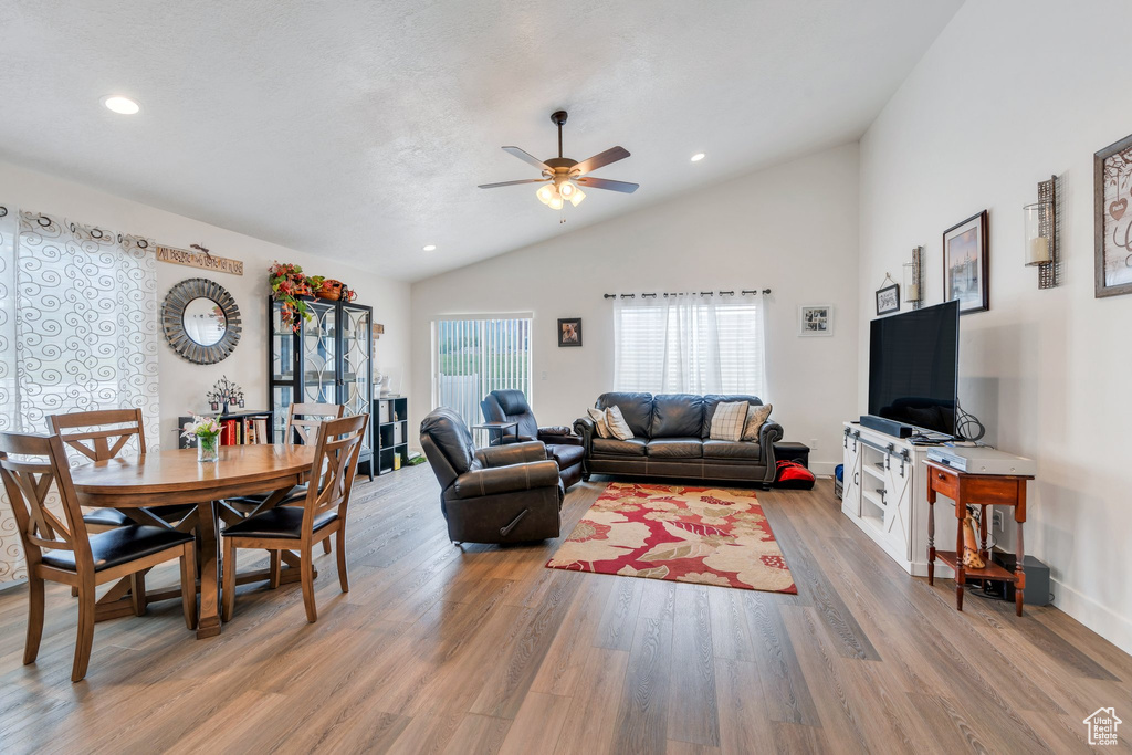 Living area with lofted ceiling, a ceiling fan, light wood-style flooring, and recessed lighting
