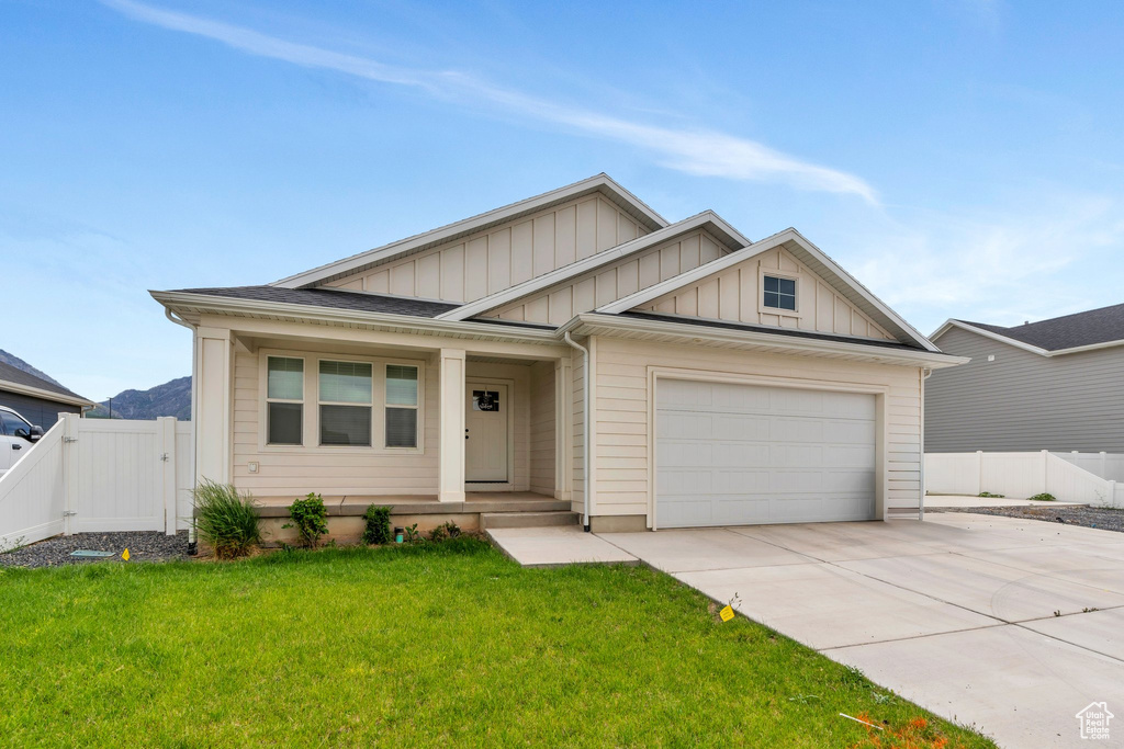 View of front facade featuring board and batten siding, driveway, an attached garage, a porch, and a gate