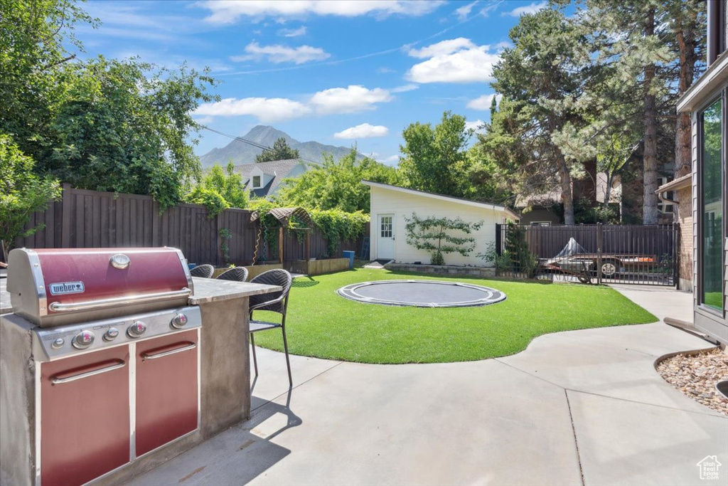 Fenced backyard with a mountain view, a patio, area for grilling, and an outbuilding