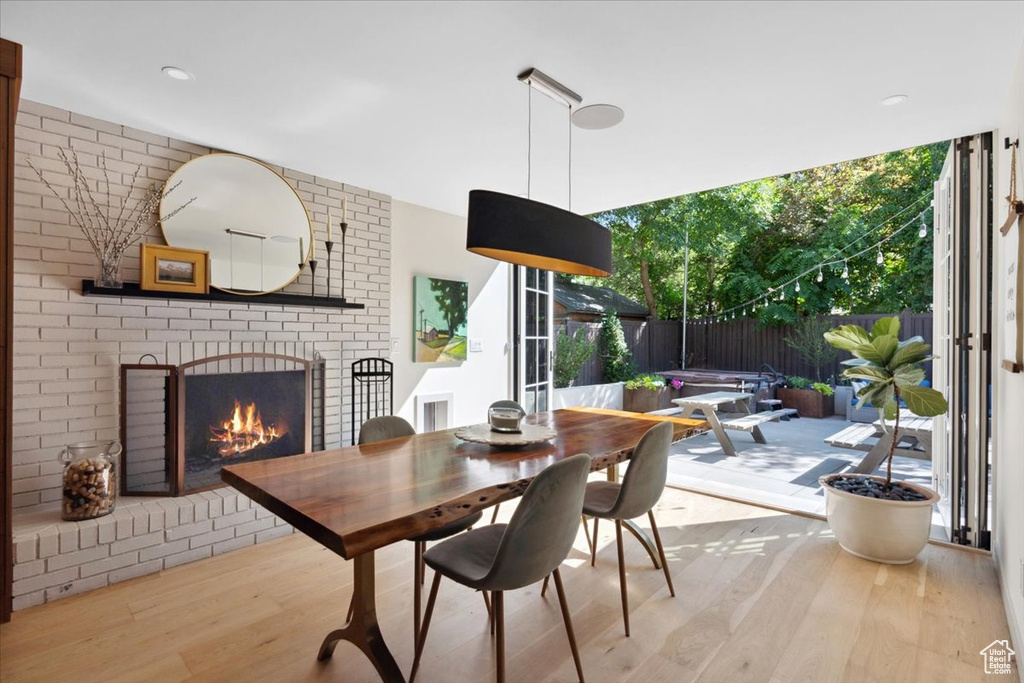 Dining room with wood finished floors, a brick fireplace, and a wall of windows