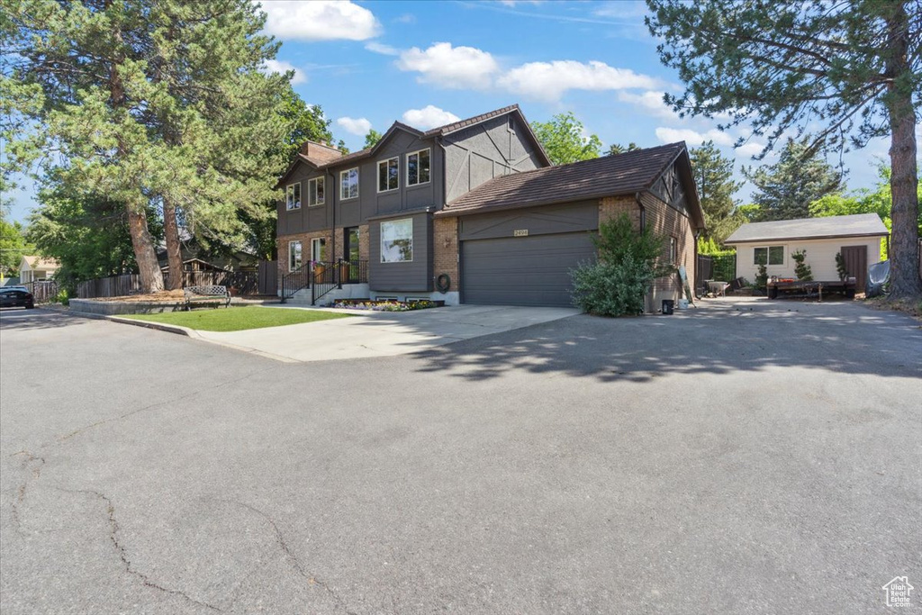 View of property featuring an attached garage, concrete driveway, and brick siding
