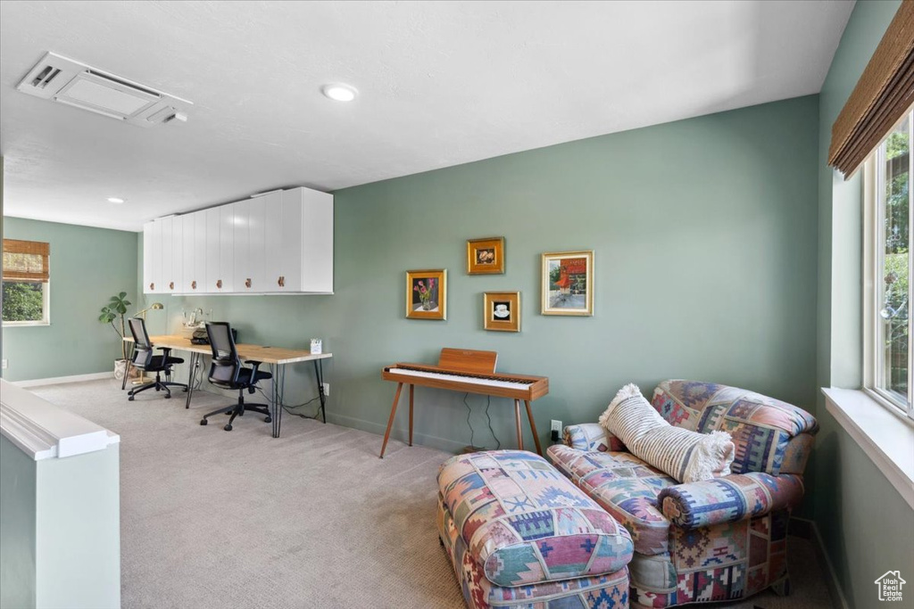 Home office with light colored carpet and recessed lighting
