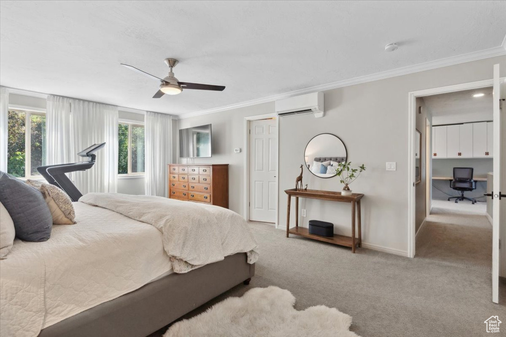 Bedroom with a wall unit AC, ornamental molding, carpet, an office area, and a ceiling fan