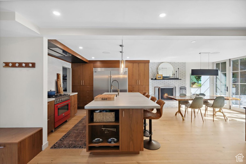 Kitchen with premium appliances, light wood-style floors, brown cabinetry, modern cabinets, and recessed lighting