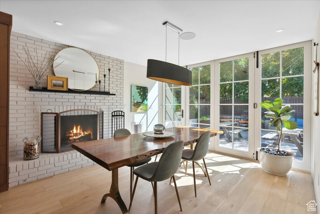 Dining space with wood finished floors, a brick fireplace, and recessed lighting