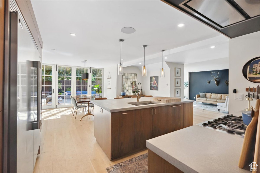 Kitchen with appliances with stainless steel finishes, light wood finished floors, open floor plan, modern cabinets, and light countertops