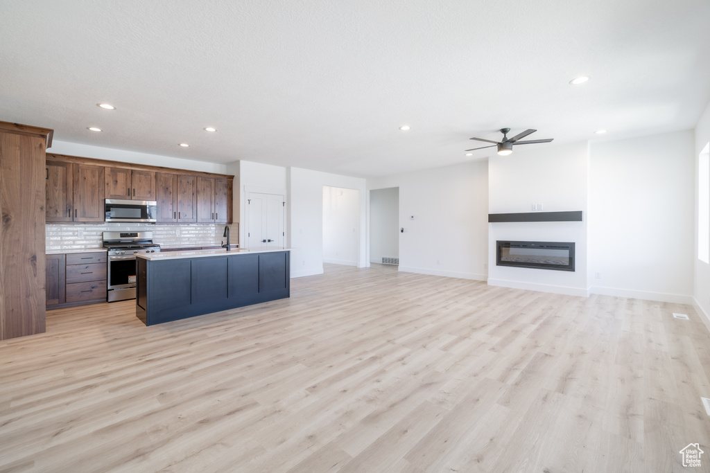 Kitchen featuring stainless steel appliances, recessed lighting, a ceiling fan, decorative backsplash, and open floor plan