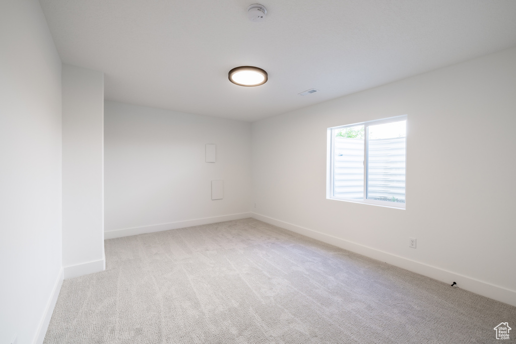 Carpeted spare room featuring baseboards and a smoke detector