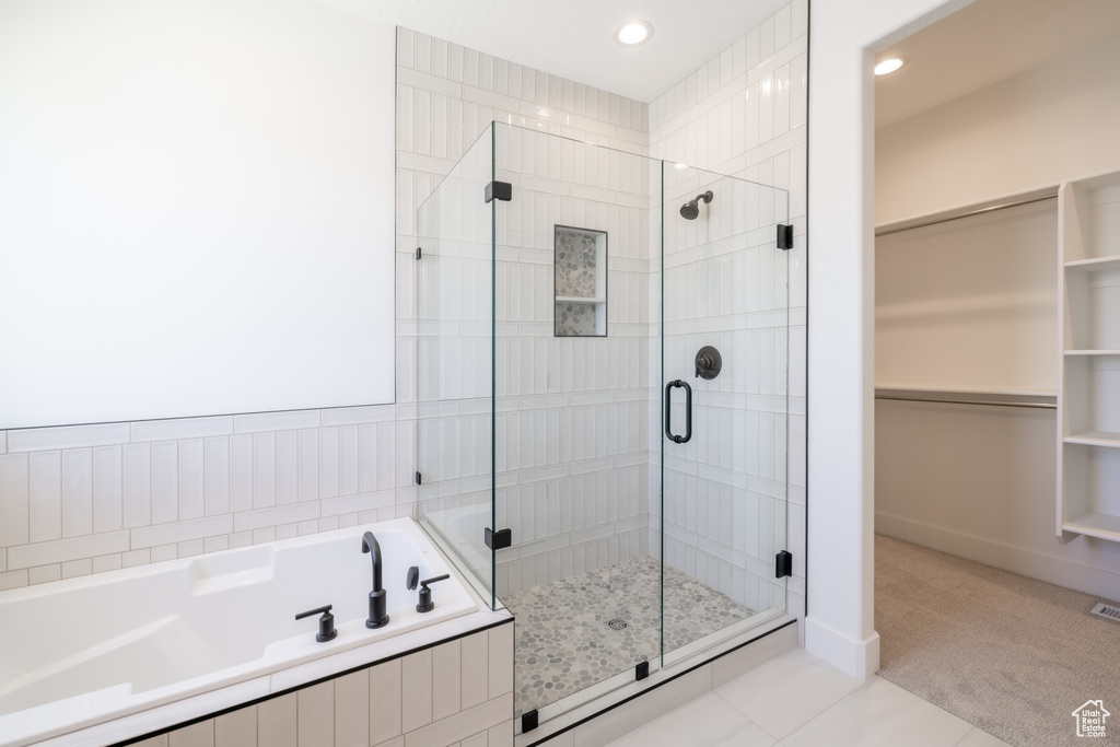 Full bathroom with a stall shower, a garden tub, a walk in closet, recessed lighting, and tile patterned flooring