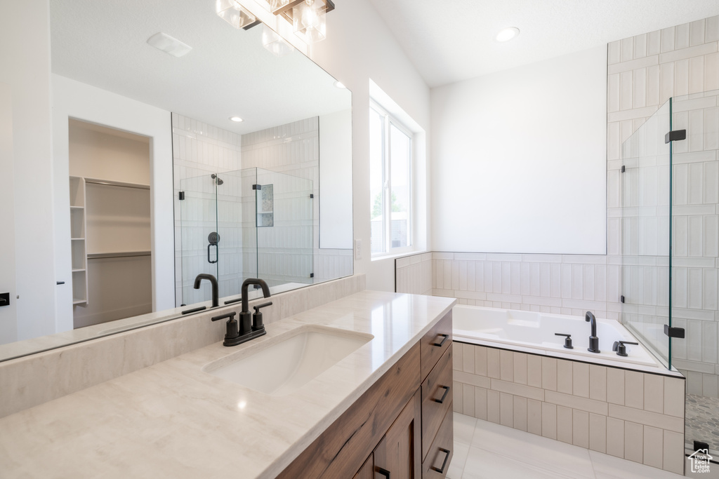 Full bath featuring vanity, a shower stall, a bath, and tile patterned flooring
