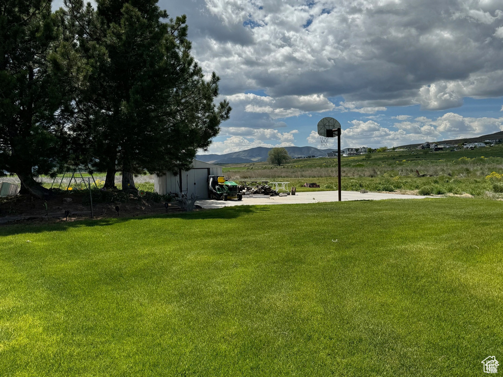 View of green lawn featuring a mountain view, an outbuilding, and a view of countryside
