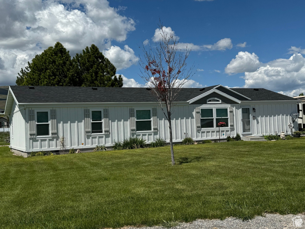 Manufactured / mobile home with board and batten siding, a front yard, and roof with shingles