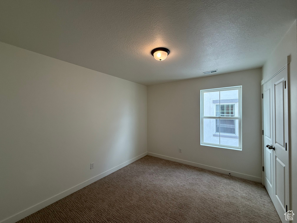 Empty room with carpet flooring and a textured ceiling