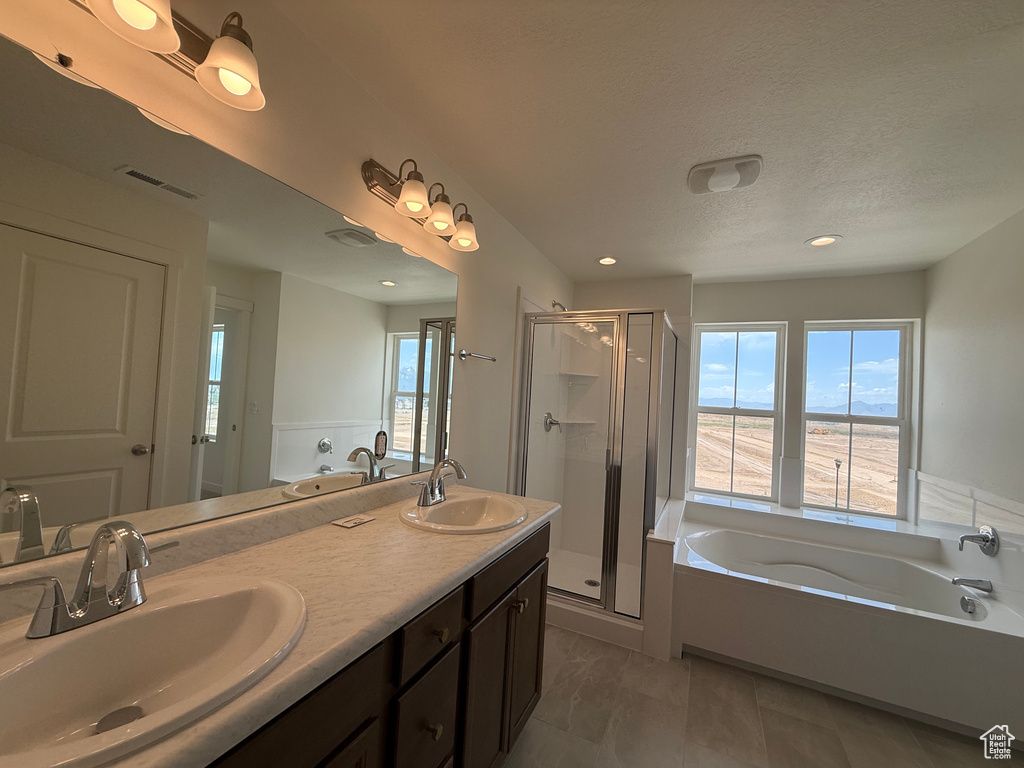 Bathroom with a garden tub, healthy amount of natural light, a stall shower, double vanity, and recessed lighting