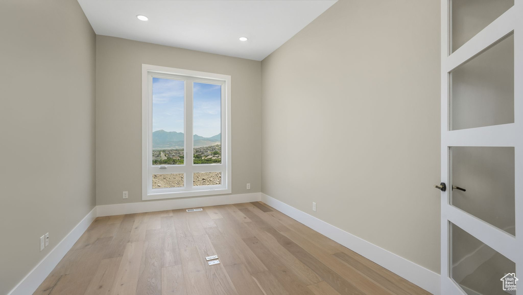 Spare room featuring light wood-type flooring, a mountain view, and recessed lighting