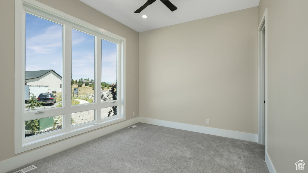 Carpeted empty room featuring healthy amount of natural light, a ceiling fan, and recessed lighting