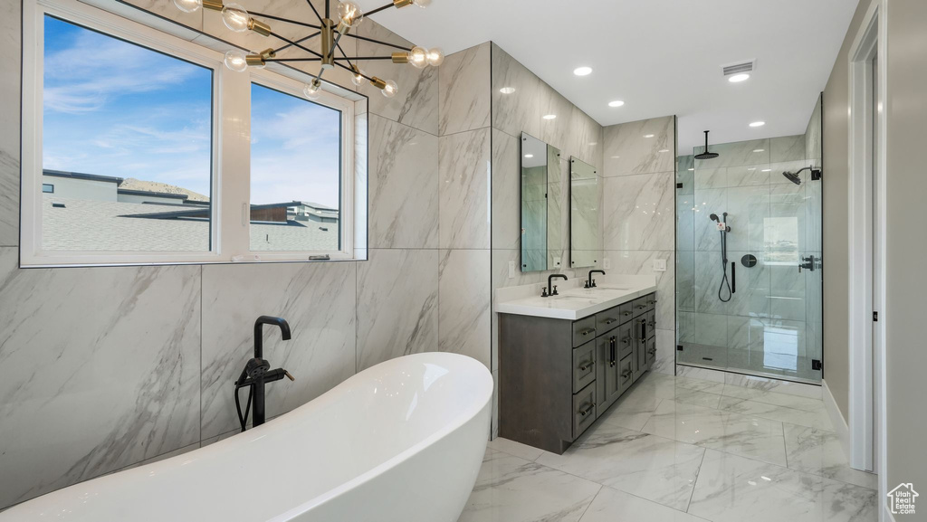 Bathroom with a stall shower, a soaking tub, tile walls, vanity, and marble tiled flooring
