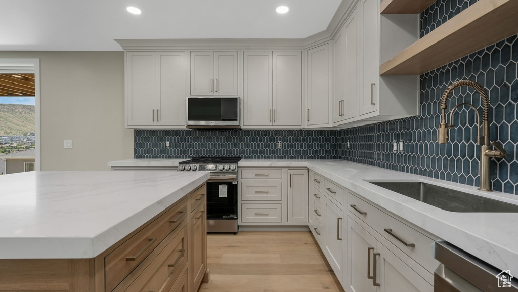 Kitchen with stainless steel appliances, open shelves, recessed lighting, tasteful backsplash, and light wood-type flooring