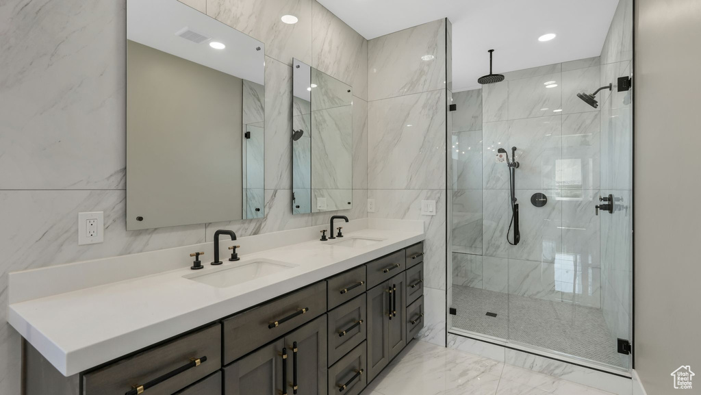 Bathroom featuring marble finish floors, double vanity, a stall shower, and tile walls