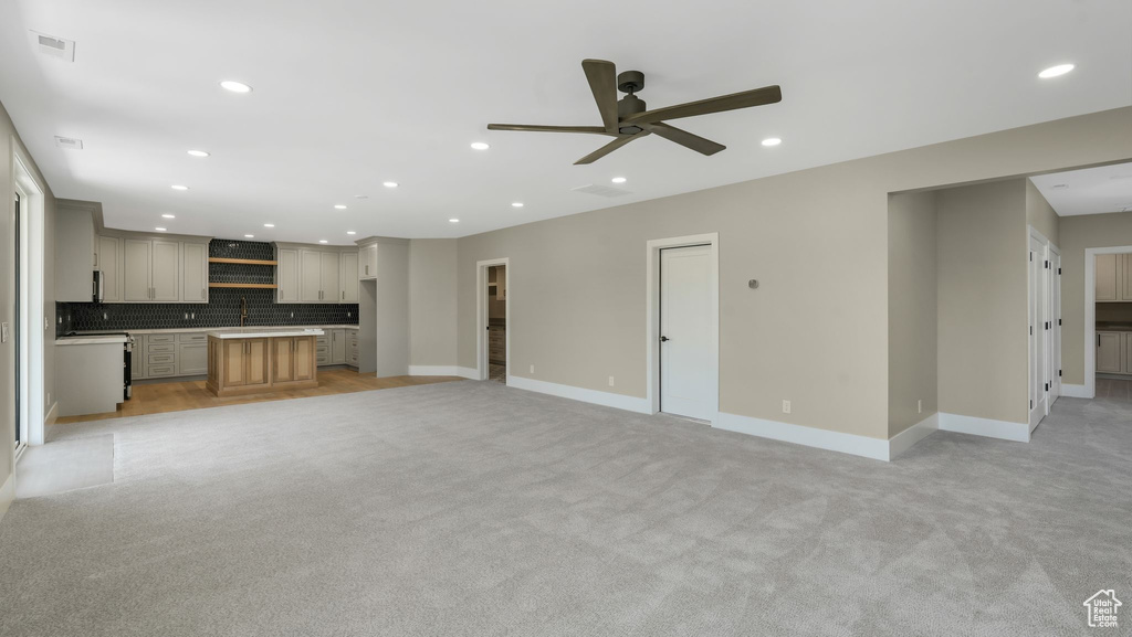 Unfurnished living room featuring light carpet, a ceiling fan, and recessed lighting