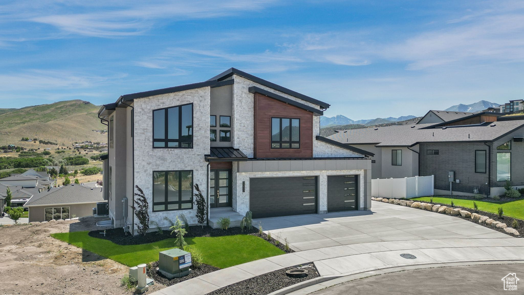 Contemporary home with a mountain view, driveway, a standing seam roof, and a garage