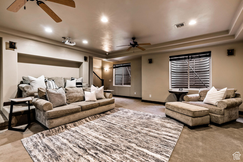 Home theater room with ceiling fan, light colored carpet, recessed lighting, and a tray ceiling