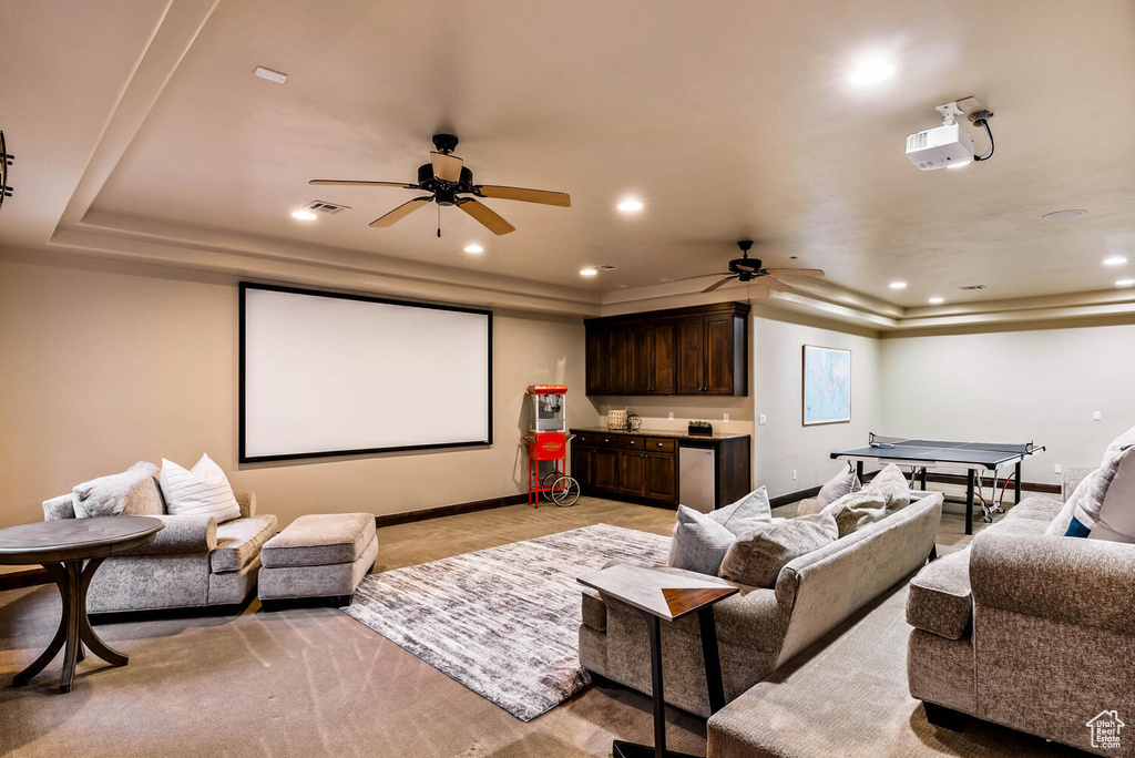 Cinema room with a raised ceiling, ceiling fan, and recessed lighting