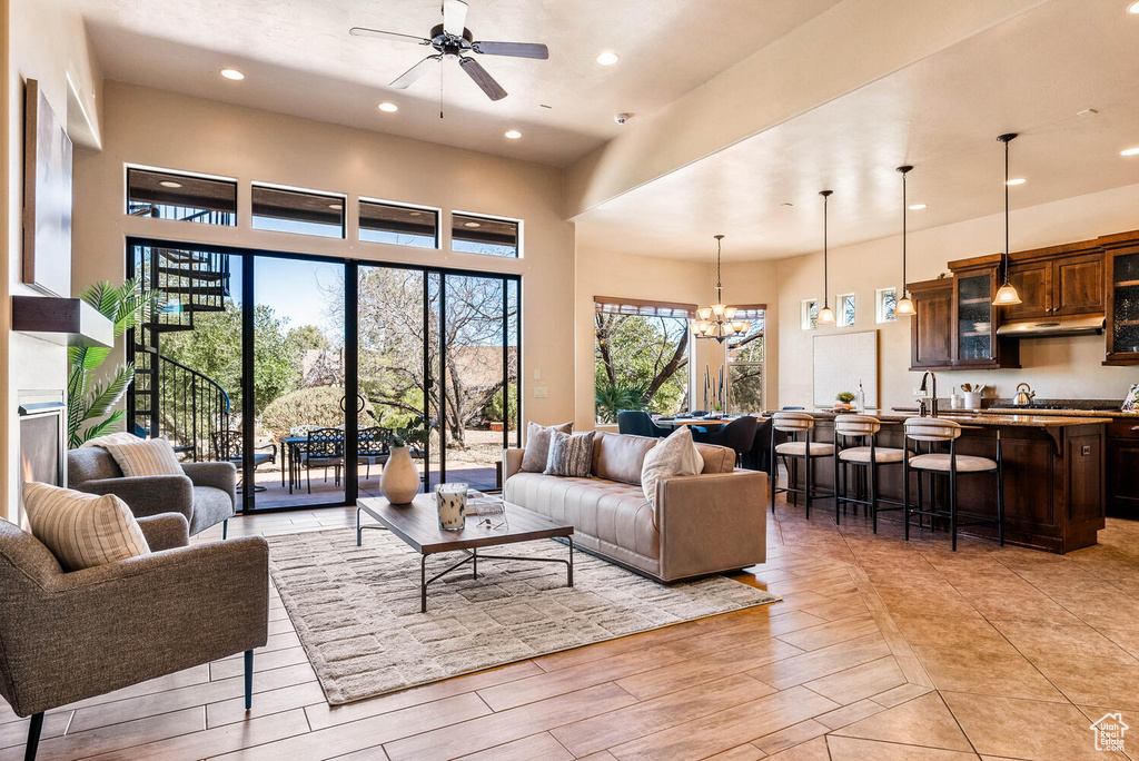 Living area with a ceiling fan, a chandelier, recessed lighting, light wood-type flooring, and a fireplace