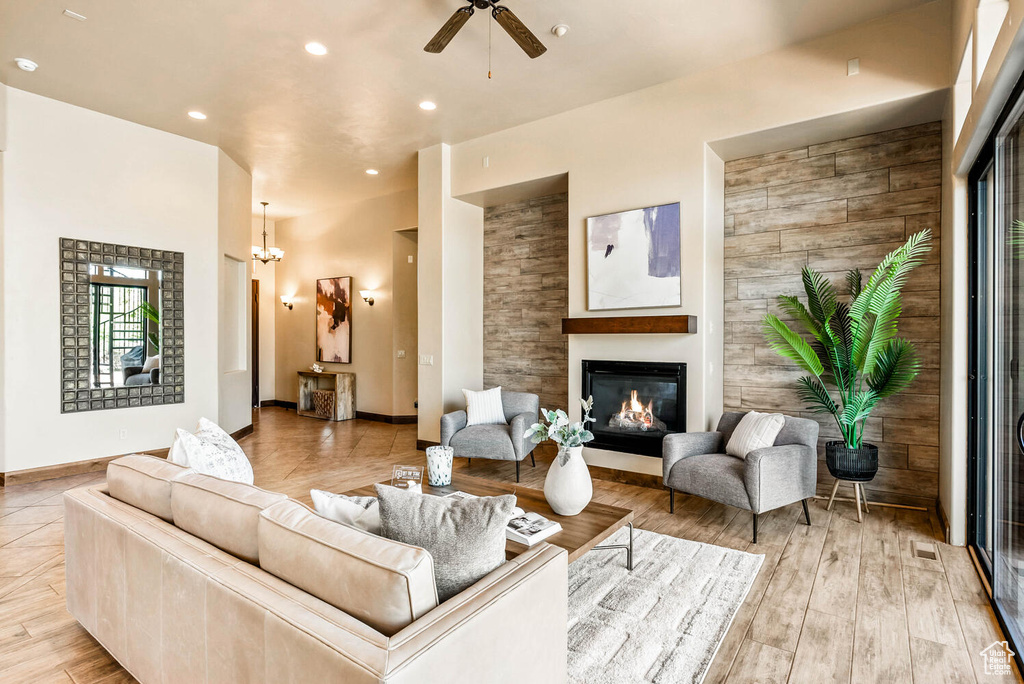 Living area featuring a glass covered fireplace, ceiling fan, recessed lighting, and wood finished floors