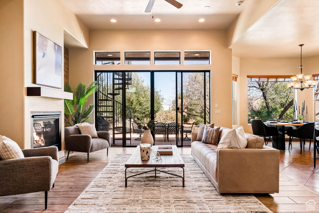 Living room featuring a chandelier, ceiling fan, a glass covered fireplace, wood finished floors, and recessed lighting