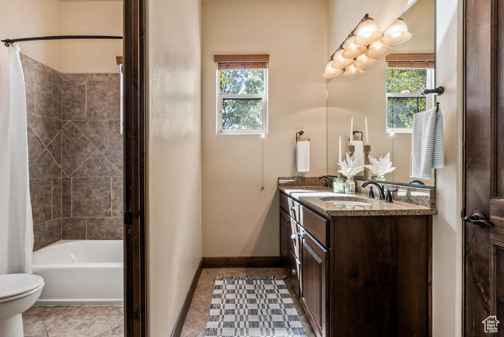 Bathroom featuring double vanity, healthy amount of natural light, shower / tub combo, and tile patterned flooring